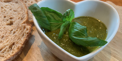 Pesto in a bowl with basil garnish and side of bread